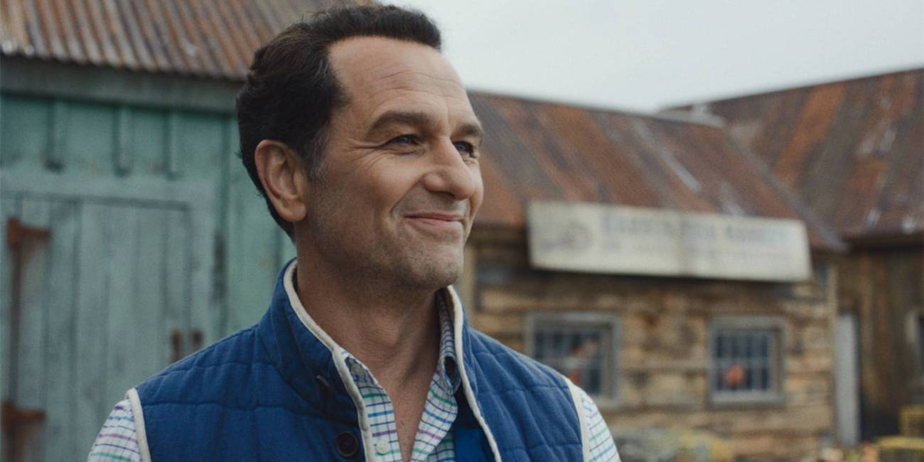 Matthew Rhys as Tom standing outside with a slight smile in Widow's Bay